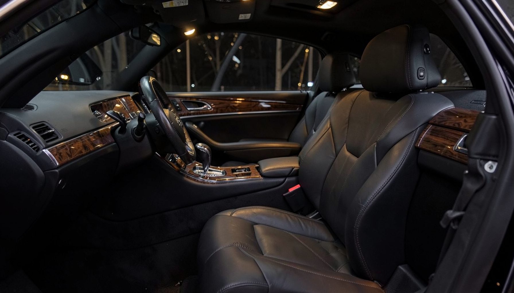 Dark luxury sedan interior with leather seats and wood trim, warm ambient lighting, elegant and professional mood