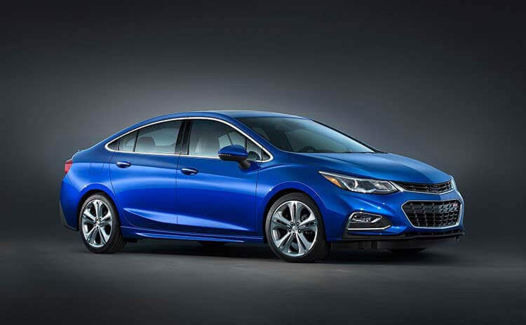 Blue sedan car shown at an angle in a dark studio setting with reflective floor