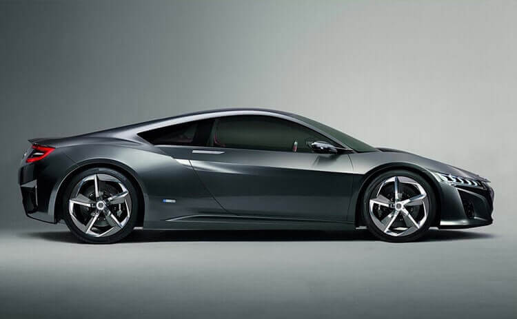 Dark grey sports coupe photographed in side profile against a plain grey studio backdrop, sleek and minimal mood