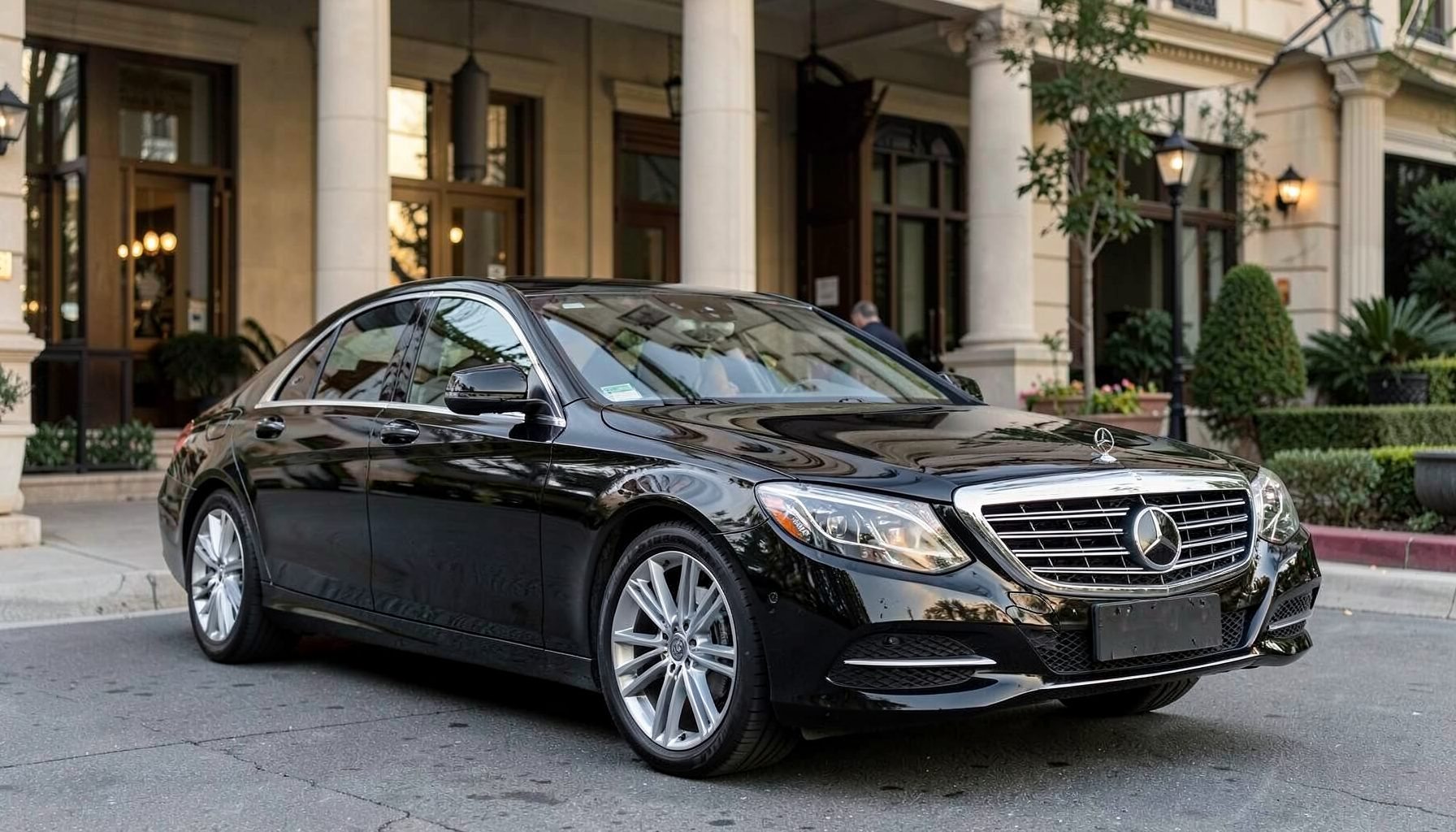 Black Mercedes Benz E Class sedan with elegant lines and chrome detailing, parked outside a grand hotel entrance